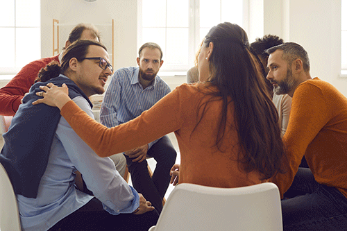 a group of people comfort a person in a cocaine addiction treatment program