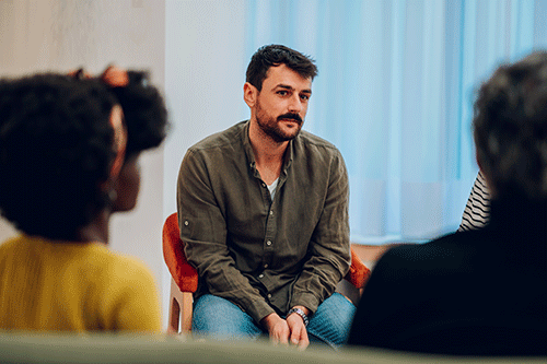 sincere young man participates in a group session as part of an aftercare program for addiction recovery