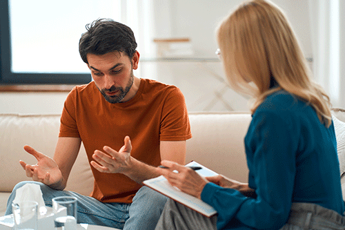 young man with concerned expression speak to therapist about meth addiction center programs