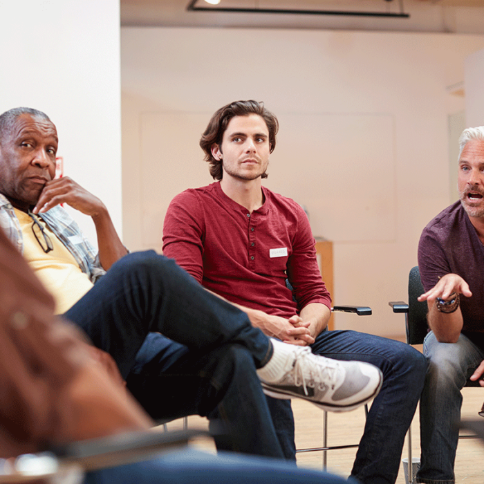 Therapist explaining to a group of men with substance use disorders why they should choose a men's rehab program in Ohio