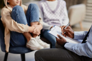 group of men and women gathered around a therapist asking could my family benefit from therapy