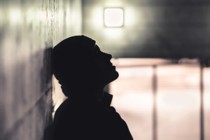 silhouette of person leaning against wall with blurred room in background wondering what are the signs of fentanyl addiction