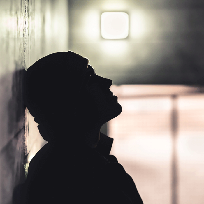 silhouette of person leaning against wall with blurred room in background wondering what are the signs of fentanyl addiction