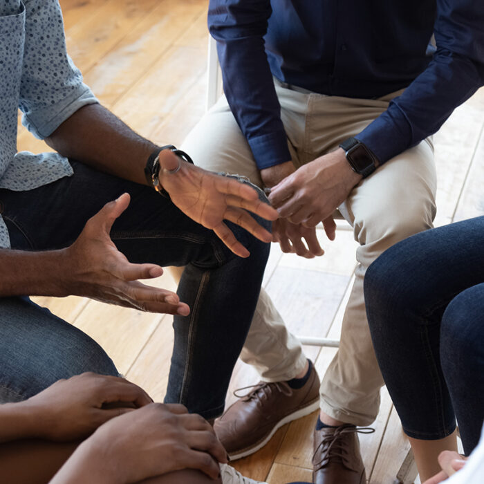 close up of several men and women seated together in a tight circle asking does group therapy work