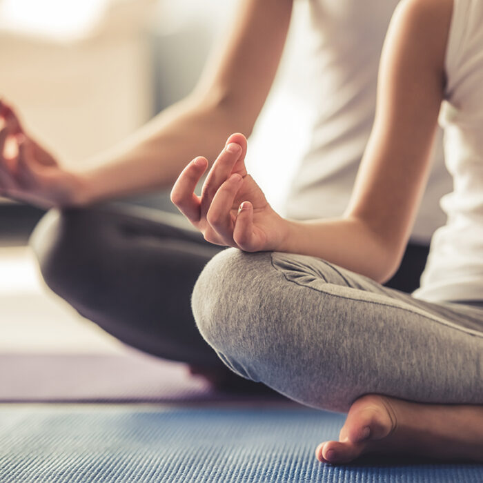 close up of men and women seated in lotus position as part of a class demonstrating what is an example of meditative therapy