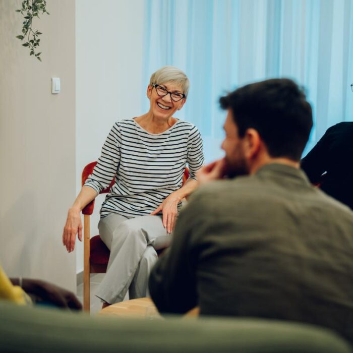 group of men and women in therapy session discussing how to help someone with trauma