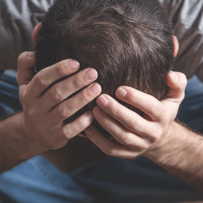 distraught man with his head in his hands desperately wanting to know what are some signs of cocaine addiction