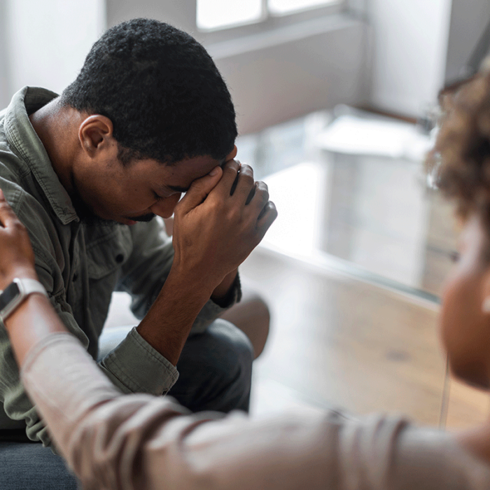 Distraught young man is consoled by therapist as she explains what are the signs of dual diagnosis